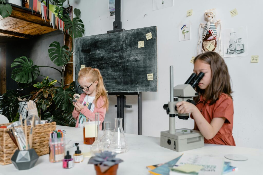 Two young girls experimenting with science equipment in a classroom setting, showcasing education and curiosity.